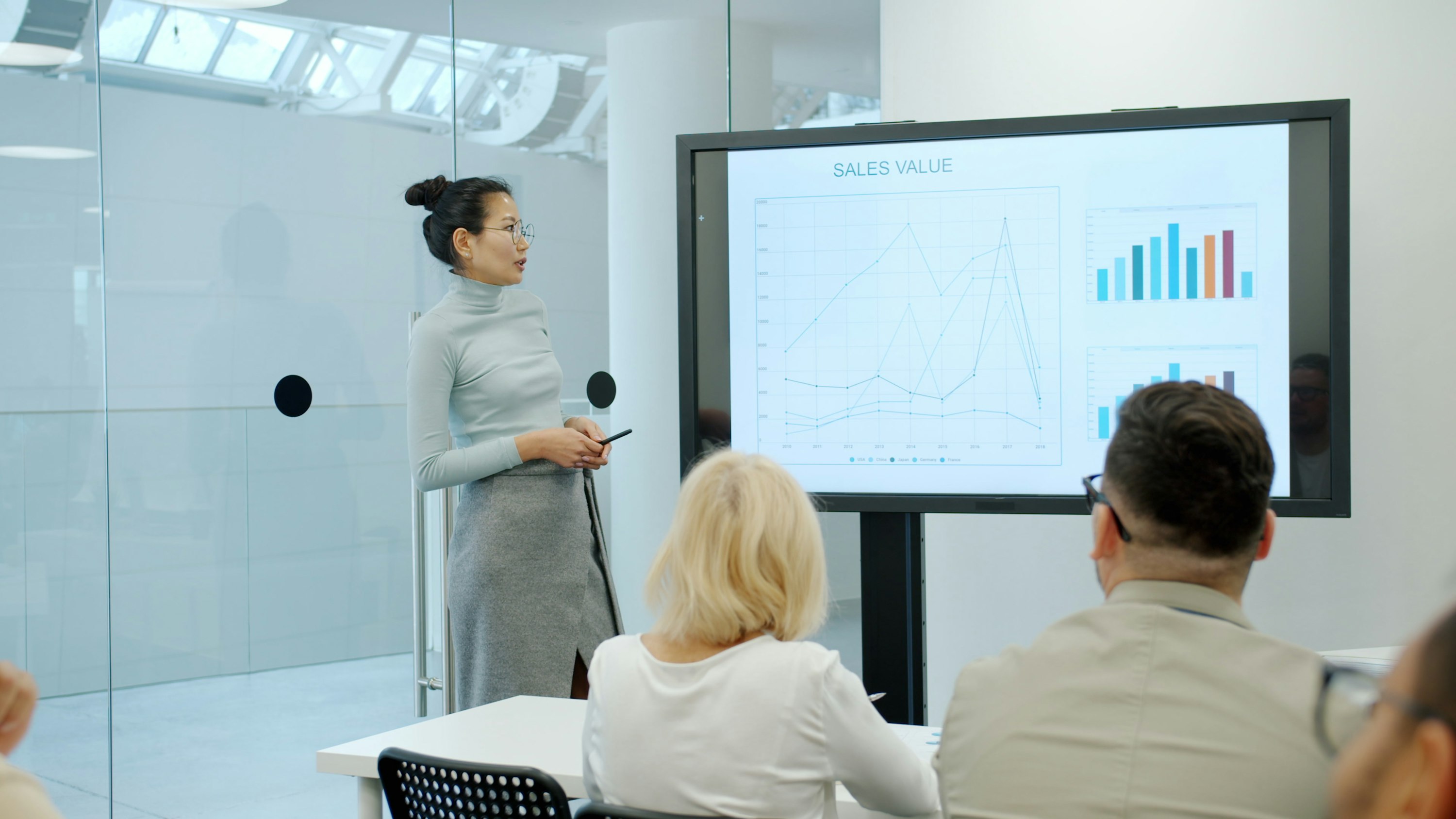 Asian speaker presenting data to a mixed training-room audience
